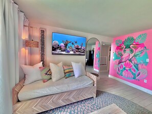 Ein modernes Wohnzimmer mit einer Couch, einem großen Spiegel und einem lebendigen Wandbild.