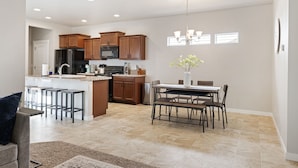 A modern kitchen with wooden cabinets, a central island, and a dining area with a table and chairs. - ❃Close to the POOL! 3BD/2BA! Close to BSU/Nampa/Kuna! Your Boise Vacation Spot!❃ (Meridian)