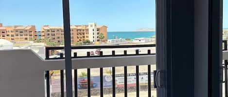 Un balcon donnant sur une plage et des immeubles.