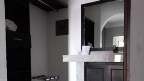 Una cocina moderna con encimera de mármol, armarios oscuros y una pequeña mesa de comedor.