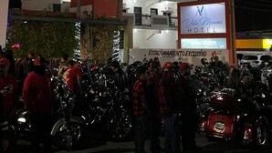 Un hotel de varios pisos con balcones, un cartel que dice Vista Marina Hotel y una multitud de personas cerca de motocicletas.