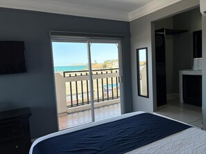 A bedroom with a bed, a TV, a balcony with a view of the sea, and a fireplace. - Hotel Vista Marina (Puerto Peñasco)