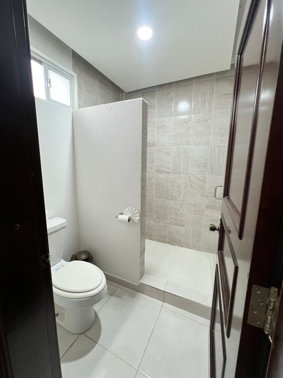 A bathroom with a toilet, a shower, and a sink.