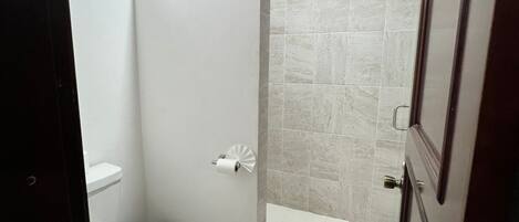 A bathroom with a toilet, a shower, and a sink.