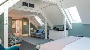 Une chambre spacieuse située dans les combles, avec un grand lit, un canapé et un coin repas.