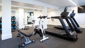 Une salle de sport équipée de tapis de course, d’un appareil elliptique et de poids libres.