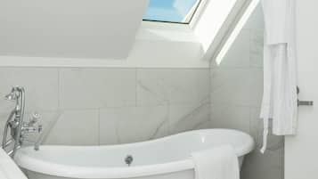A modern bathroom with a freestanding bathtub, a skylight, and a white sink.