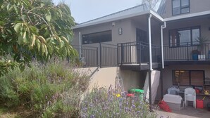 Un bâtiment à deux étages doté d’un balcon, entouré d’une végétation luxuriante et de plantes de lavande.