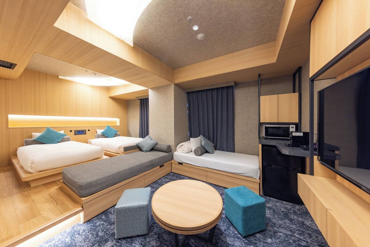 Een compacte hotelkamer met twee bedden, een eettafeltje, een magnetron en een televisie.
