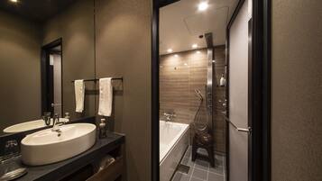 A modern bathroom with a large sink, a mirror, and a shower area.