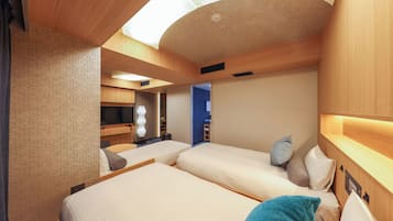 A compact hotel room with two beds, a ceiling light, and a small desk area.