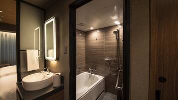 A modern bathroom with a large mirror, a sink, and a bathtub.