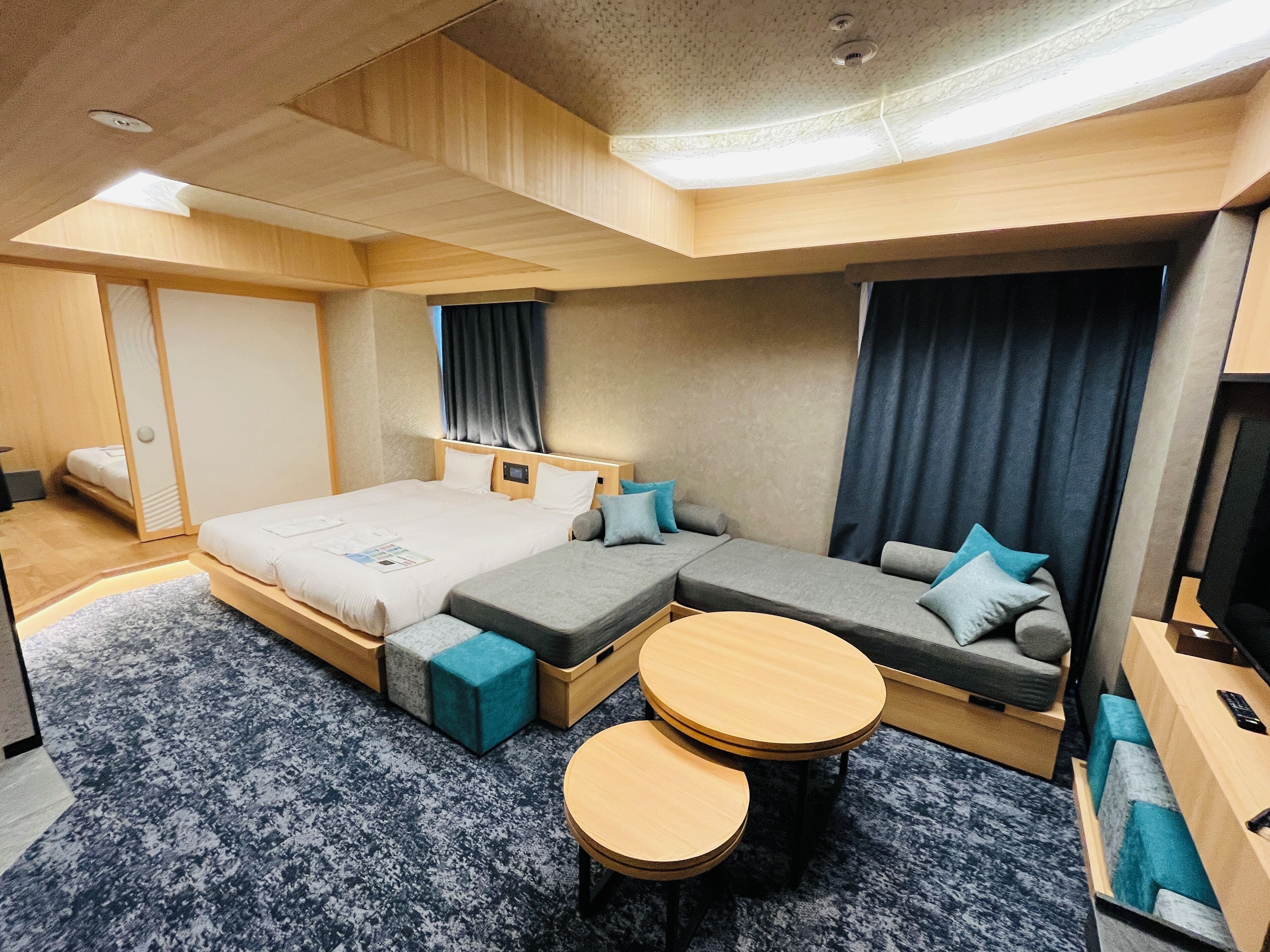 A modern hotel room with a large bed, a sofa, a small table, and a TV.