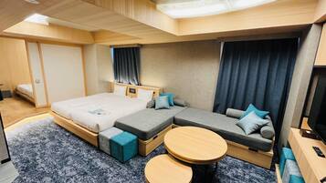 Una habitación de hotel moderna con una cama grande, un sofá, una mesita y un televisor.