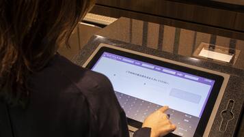 Eine Person bedient einen Touchscreen-Kiosk in der Hotelhalle.