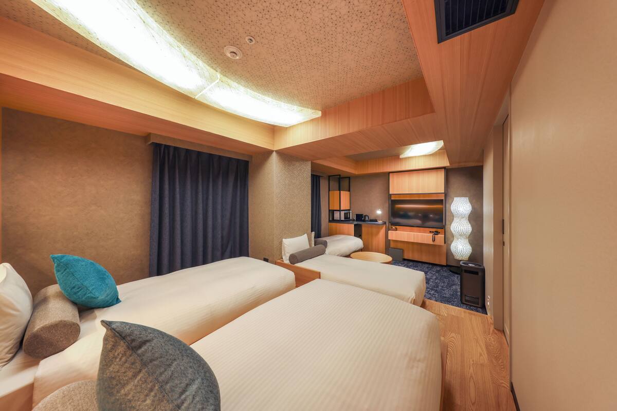 Een hotelkamer met twee bedden, een klein bureau, een televisie en een badkamer.