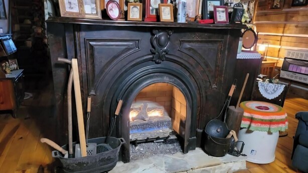 A fireplace with a stone hearth, a wooden bucket, a pot, and a colorful cloth.