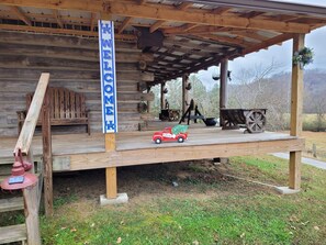 Une structure rustique en bois, agrémentée d’une pancarte « BIENVENUE », d’une petite voiture jouet rouge et d’un banc en bois.