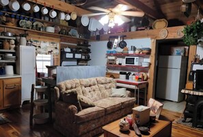 Una cocina acogedora con techo de madera, un sofá, una mesa de comedor y varios electrodomésticos.