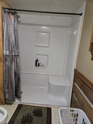 A bathroom with a shower, toilet, and a basket.