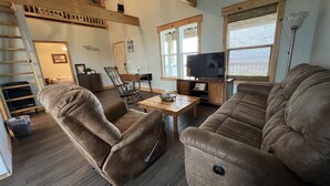 A living room with a sofa, a recliner, a TV, and a dining table. - Waterfront!! Private Pier! Reel Relaxing, Real Fun On Sabine Lake (Port Arthur)