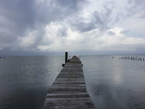 A wooden pier extending into calm water under a cloudy sky.