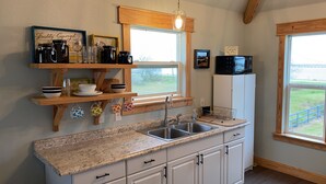A kitchen with a granite countertop, white cabinets, a stainless steel sink, and wooden shelves above the counter. - Waterfront!! Private Pier! Reel Relaxing, Real Fun On Sabine Lake (Port Arthur)