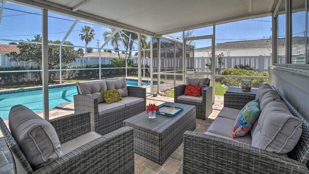 A covered patio area with wicker furniture and a view of a swimming pool.