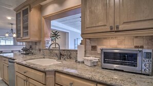 A kitchen with wooden cabinets, a granite countertop, a built-in oven, and a large window.