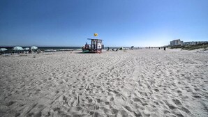 A beach with a lifeguard tower, beach chairs, umbrellas, and a clear sky.