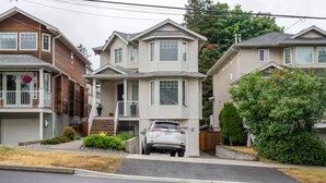 A two-story residential house with a front porch, a garage, and a driveway. - Private Suite!! Convenient location for Commuters, Essential Workers and Trades! (New Westminster)