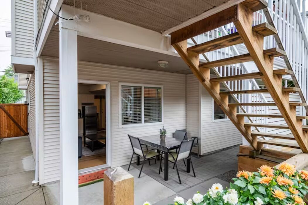 Une terrasse couverte avec un escalier en bois, une table et des chaises, et une vue sur l’intérieur de la maison.