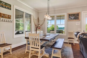 A dining area with a table and chairs, a hanging light fixture, and a view of the outdoors. - Sleeps 18, Super Spacious, New Patio, Hot Tub, Best Location on the Lake (Silver Point)