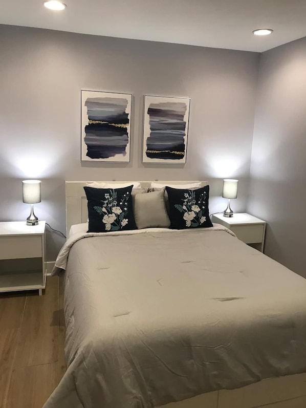 A bedroom with a large bed, two nightstands, and two wall-mounted lamps.
