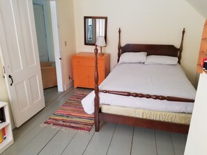 Une chambre à coucher avec un lit en bois, une table de chevet, une commode et un tapis coloré.