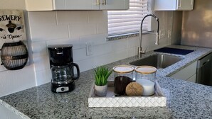 Una cucina con una macchina da caffè, una pianta in vaso e barattoli sul bancone.