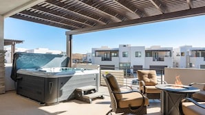 A rooftop patio with a hot tub, outdoor seating, and a view of modern buildings. - Camelot by RedAwning (St. George)