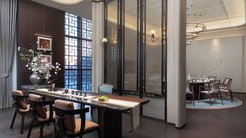 A modern dining area with a long table, chairs, and a vase of flowers.