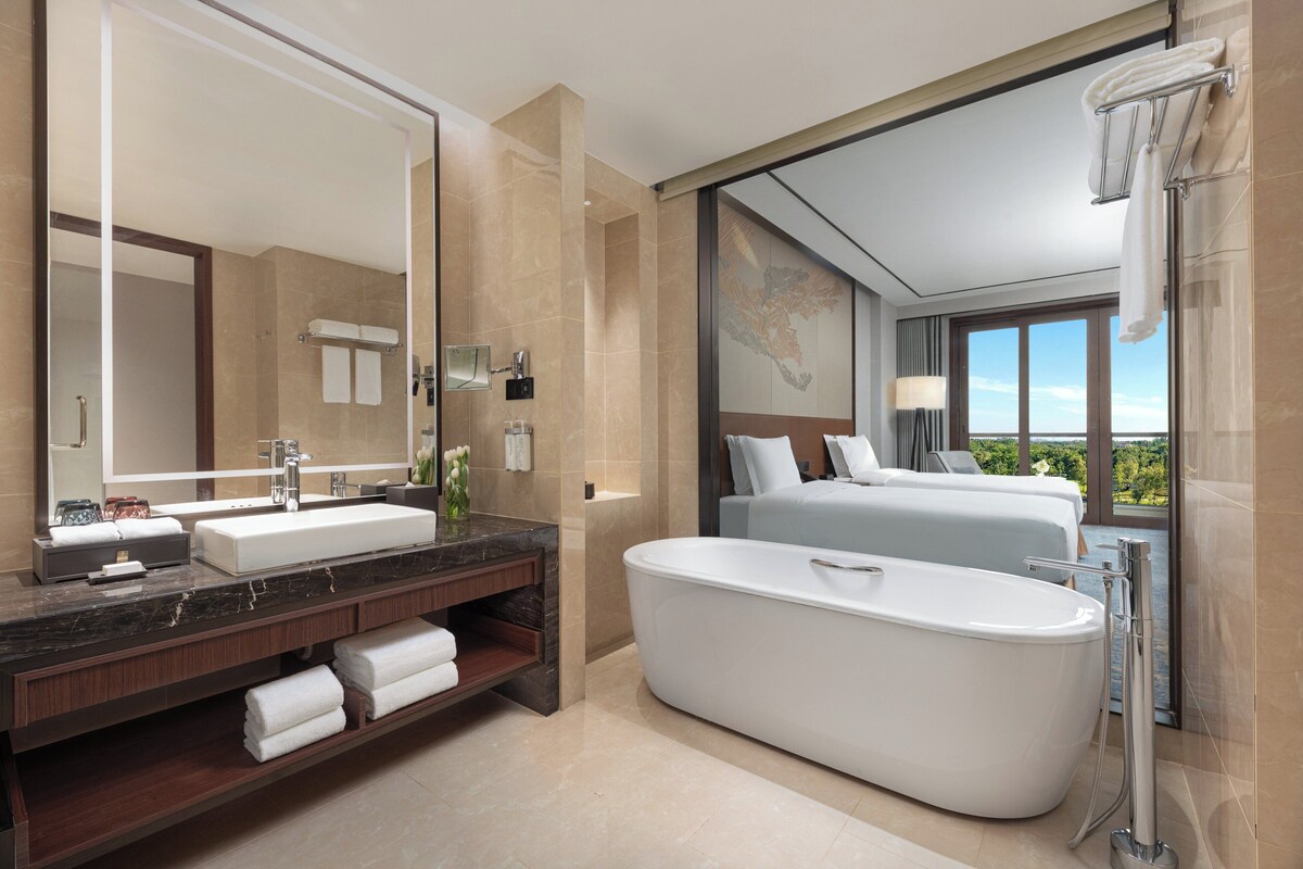 A modern bathroom with a large bathtub, a double sink vanity, and a large mirror.
