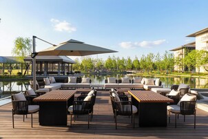 Una terraza con asientos al aire libre, una piscina y vista a un edificio al otro lado del agua.