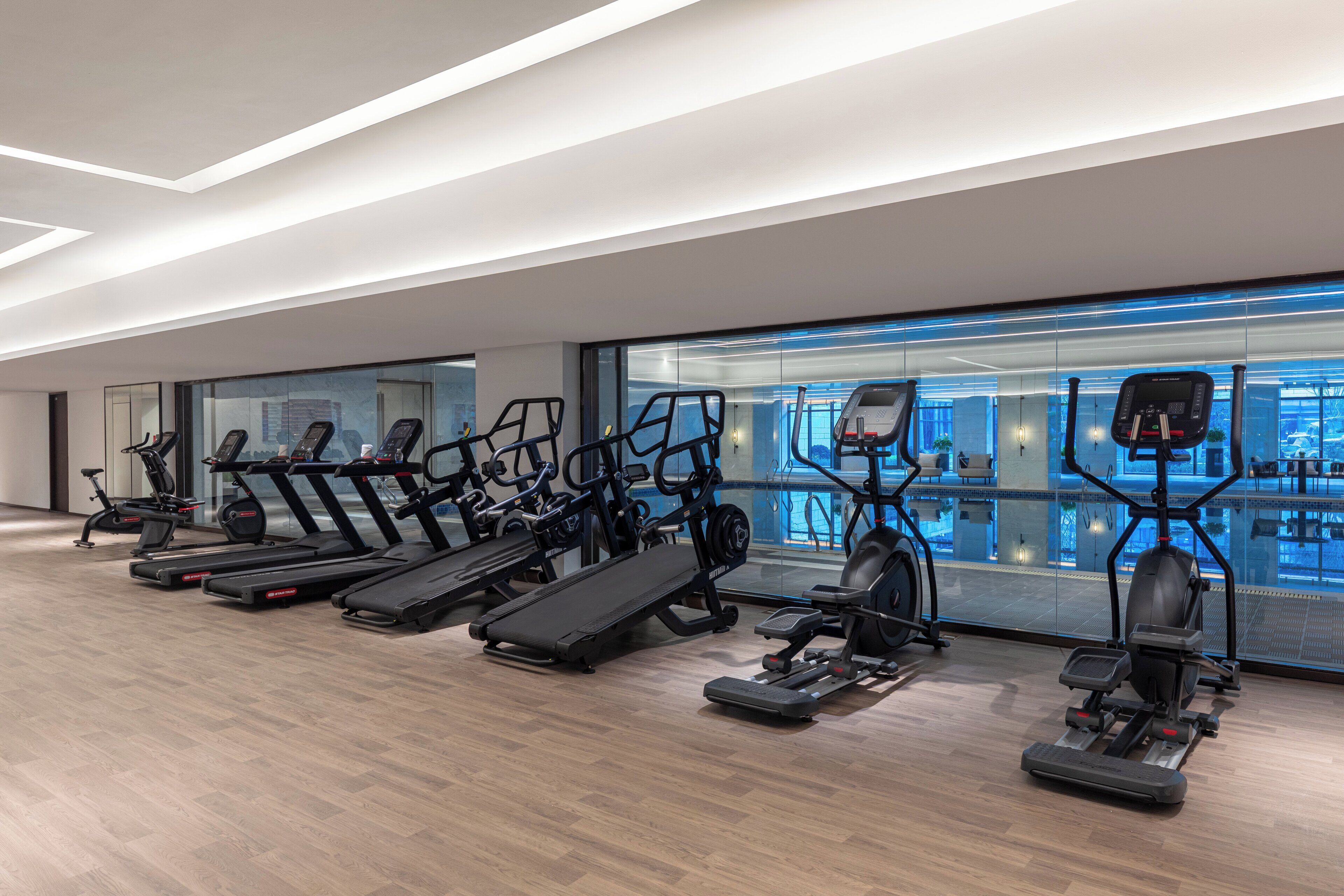 Un gimnasio moderno con cintas de correr, elípticas y una máquina de remo.