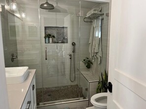 Een bad/douchecombinatie, handdoeken, zeep, toiletpapier