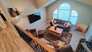 A spacious living room with a brown leather sofa, a coffee table, and a flat-screen TV mounted on the wall. - Amazing 3 Bedrooms / 2 Bathrooms home with PRIVATE HOT TUB!!! (West Jordan)