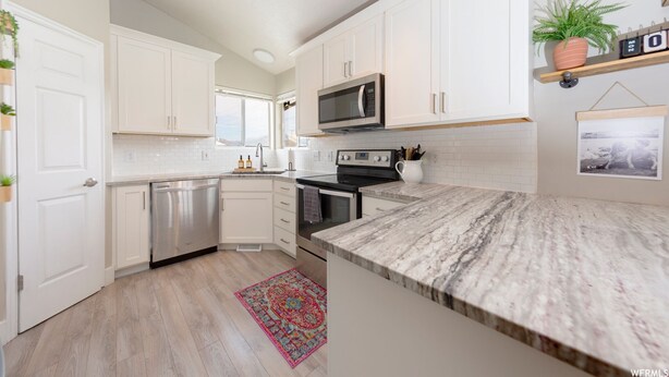 A modern kitchen with white cabinets, stainless steel appliances, and a marble countertop. - Amazing 3 Bedrooms / 2 Bathrooms home with PRIVATE HOT TUB!!! (West Jordan)