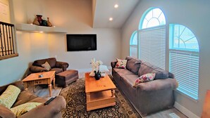 A living room with two sofas, a coffee table, a TV, and a large window with blinds. - Amazing 3 Bedrooms / 2 Bathrooms home with PRIVATE HOT TUB!!! (West Jordan)