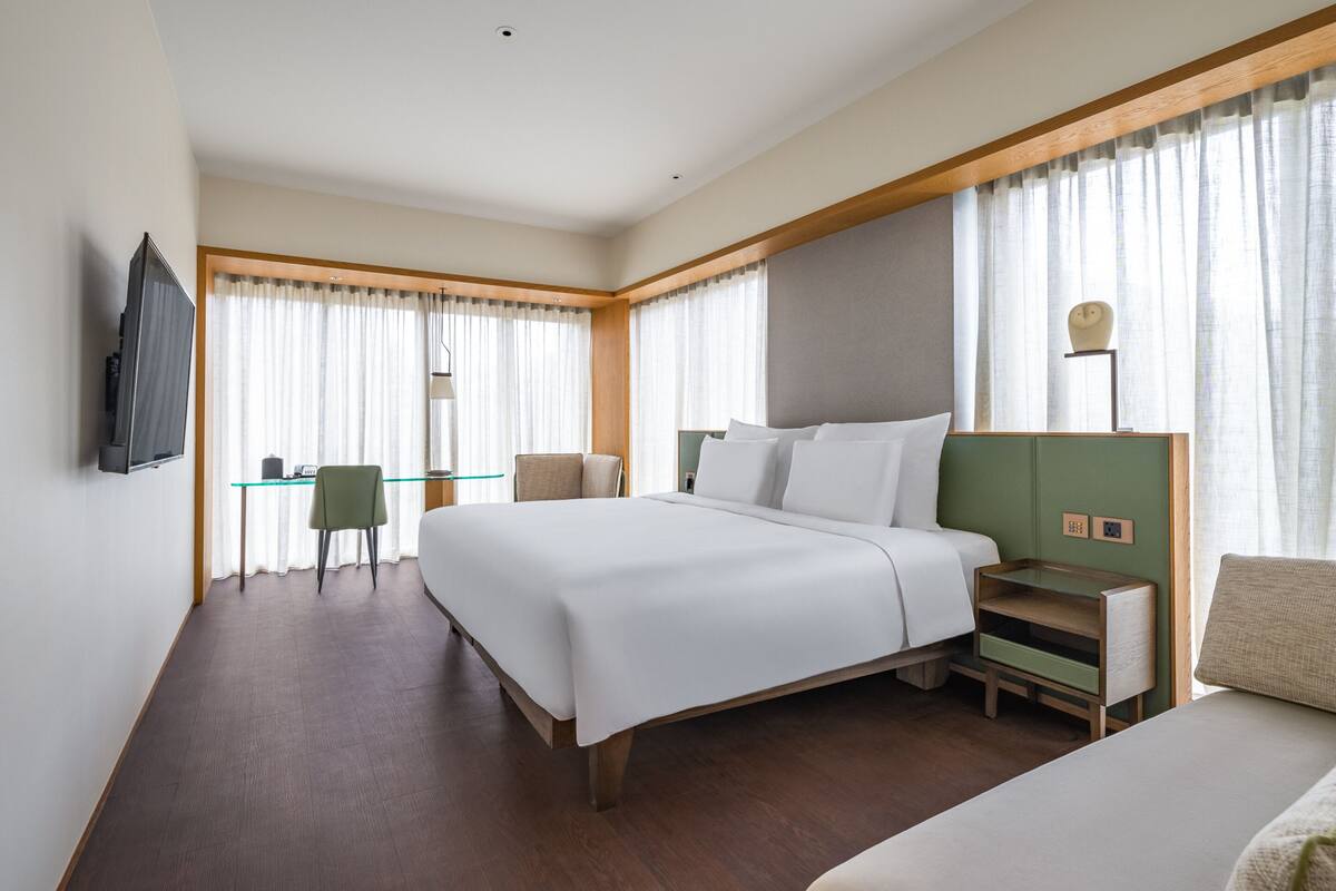 Ein modernes Hotelzimmer mit einem großen Bett, einem Schreibtisch und einem Stuhl.
