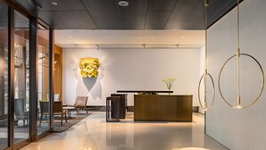 A modern reception area with a reception desk, seating, and a decorative wall piece. - Humble Boutique Hotel (Taipei)