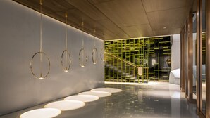 A modern interior with a reflective floor, hanging circular light fixtures, and a geometric wall design. - Humble Boutique Hotel (Taipei)