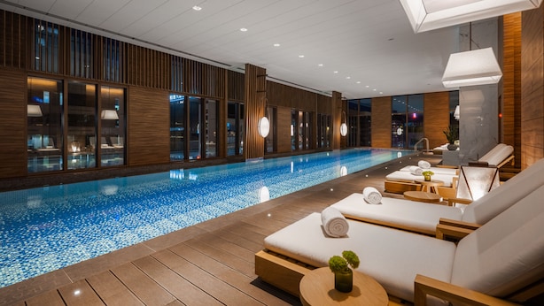 A modern indoor swimming pool with wooden flooring, lounge chairs, and ambient lighting. - Humble Boutique Hotel (Taipei)