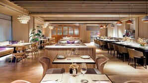 A modern restaurant with wooden flooring, long communal tables, and hanging pendant lights. - Humble Boutique Hotel (Taipei)